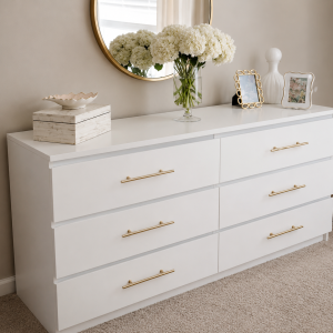 Bloom white 6-drawer chest of drawers with brass bar handles, styled beneath a round mirror with hydrangeas and photo frames