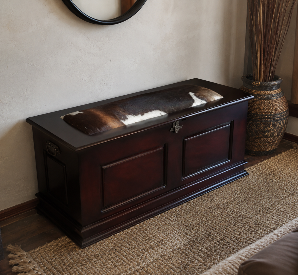 The Isiko Kist, a solid wood lobola kist with a cowhide-cushioned lid, styled in a living room