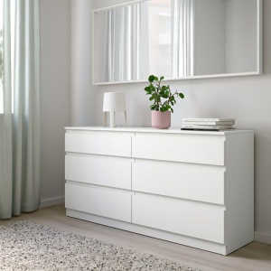 Still matte white handle-free 6-drawer chest of drawers, styled beneath a mirror with a small lamp and potted plant